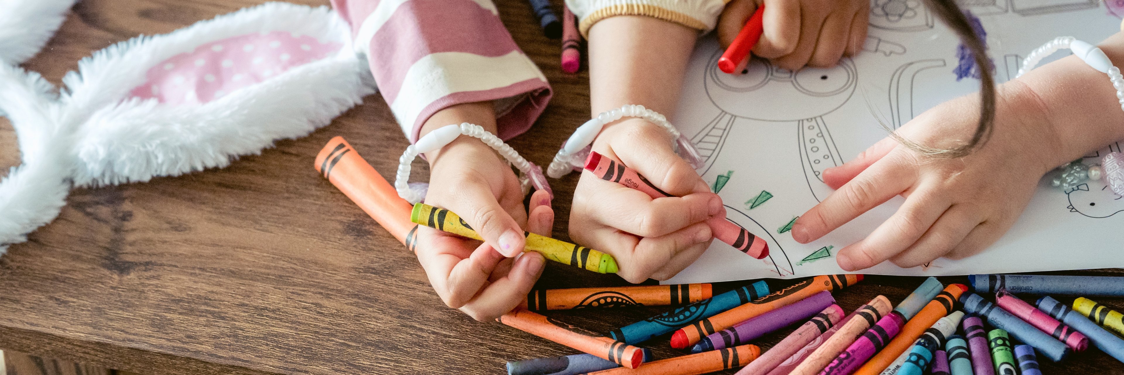 Zwei Kinder malen mit Wachsmalstifte eine Mandala aus