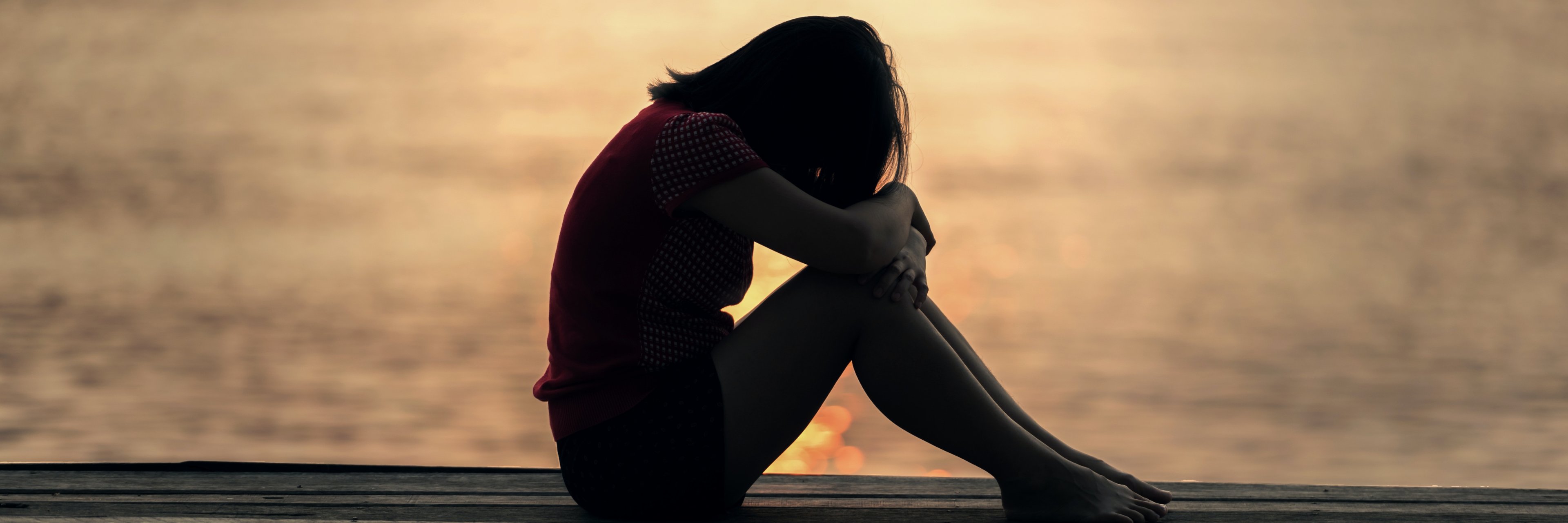 Frau sitzt einsam auf Steg